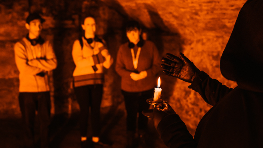 A Mercat Storyteller leading an Edinburgh underground tour in a small room of the Blair Street Underground Vaults.