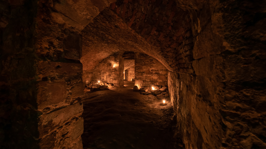 A series of candlelit stone rooms with vaulted ceilings in the Blair Street Underground Vaults, like an Edinburgh underground city.