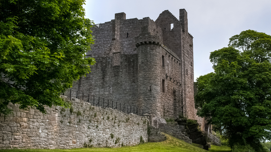 Outlander filming location Craigmillar Castle, medieval ruins surrounded by leafy green trees.