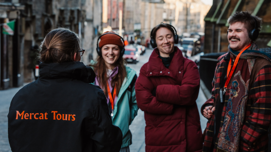 A Mercat Storyteller leading a group of 3 visitors on an Edinburgh history tour up the Royal Mile.