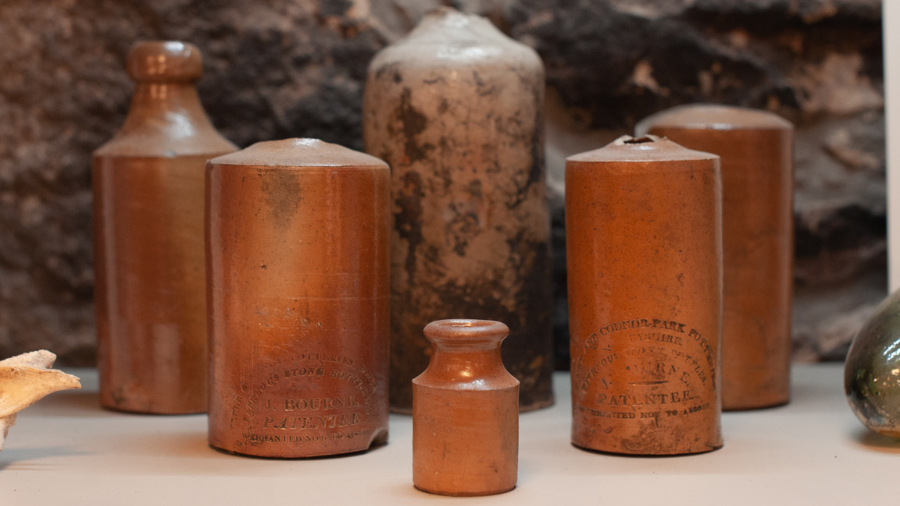 A series of stoneware bottles on display in a Mercat Tours artefacts display case. 