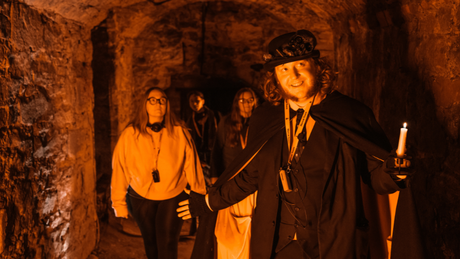 Visitors exploring one of the most haunted places in Edinburgh, the Blair Street Underground Vaults, on an Edinburgh ghost tour.