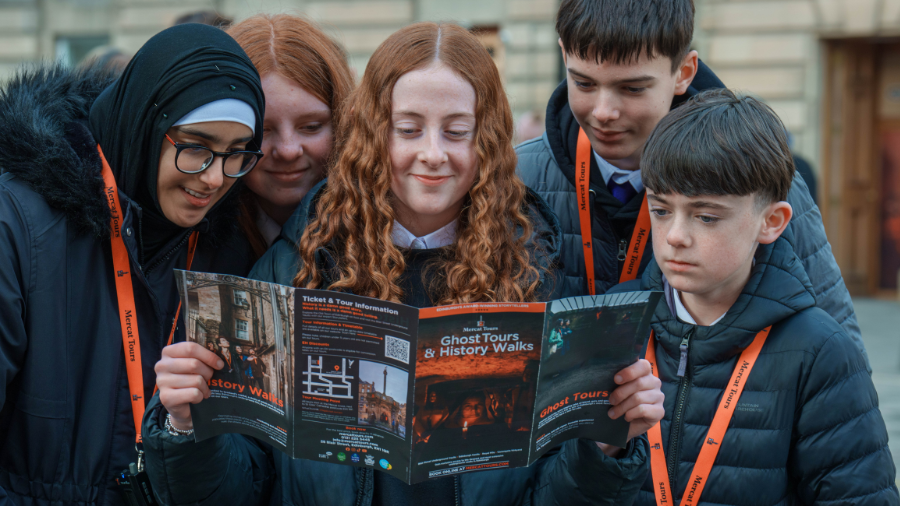 A group of 5 students from Holyrood High School look at a Mercat Tours leaflet during their 'A Day in Edinburgh' event.