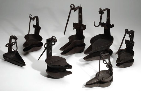A photo from National Museums Scotland of seven iron crusie lamps. 