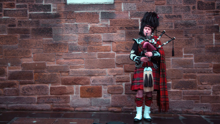 A Scottish bagpiper in a kilt playing on the Royal Mile in Edinburgh. 