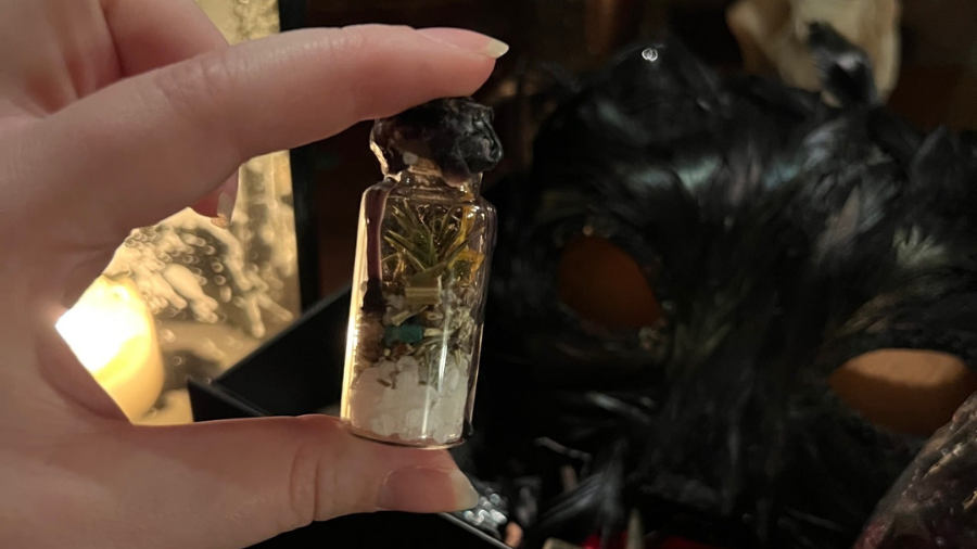 A hand holding a small spell jar of salt, crystals and herbs, meant to give protection during Edinburgh Halloween.