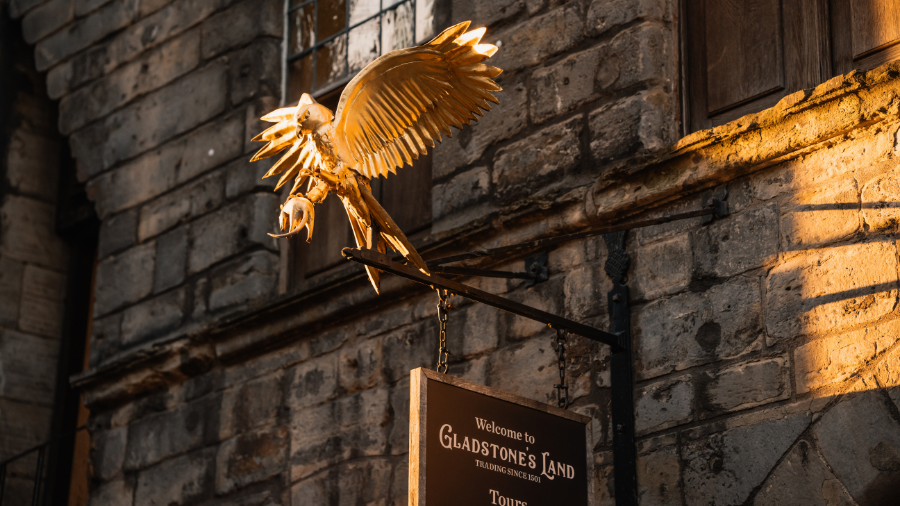 The front sign of Gladstones Land topped by a golden bird of prey, ready to welcome Halloween Edinburgh interactive tours.